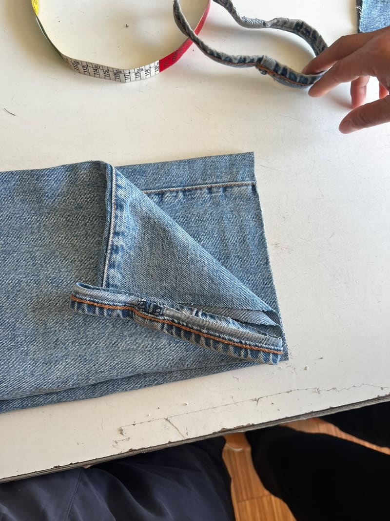 Dobladillo de basta en proceso sobre un jean en el taller de Costuras Adry